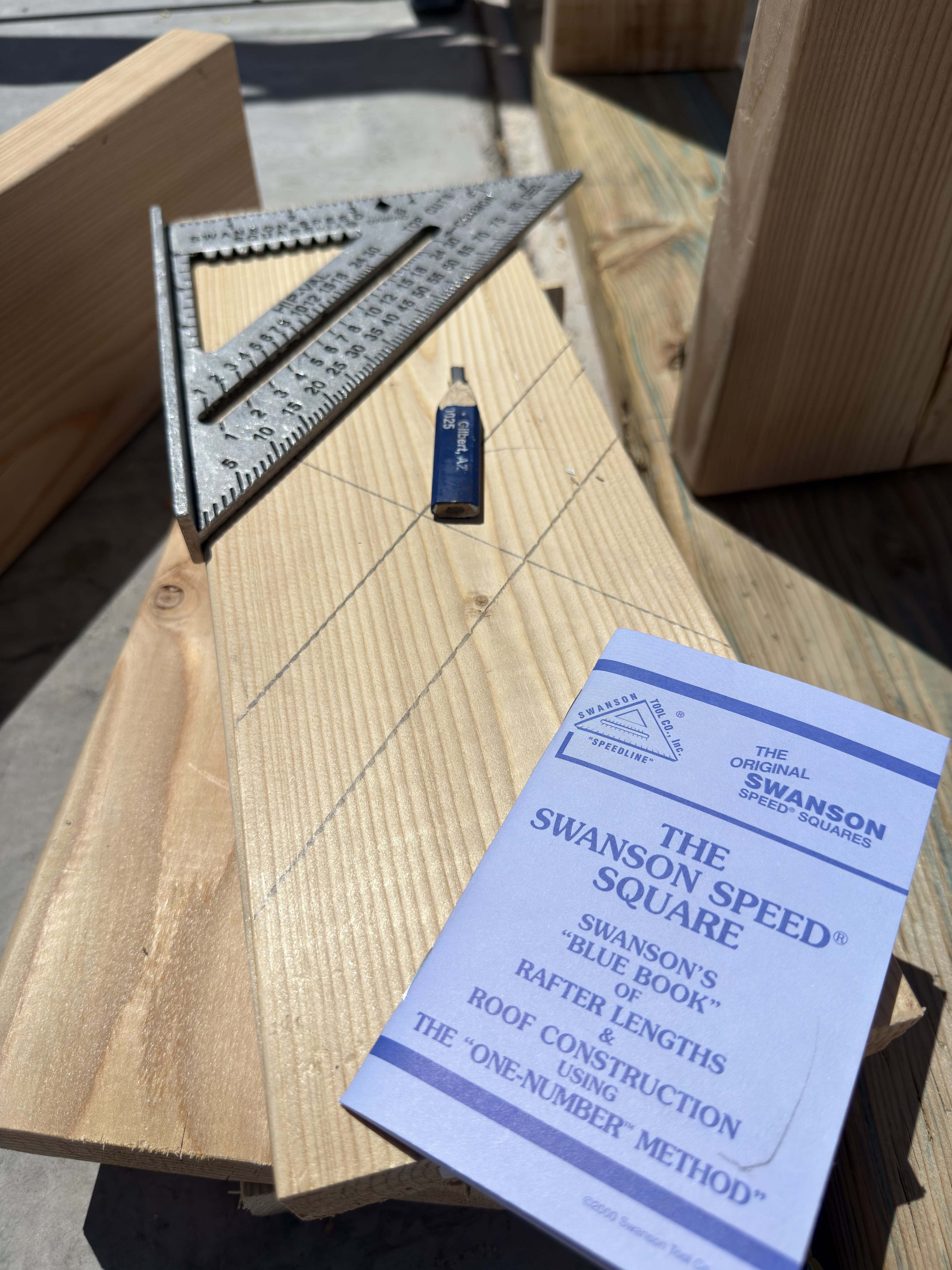Arizona jobsite shot of a Swanson Speed® Square on framing lumber next to the Blue Book showing rafter tables.