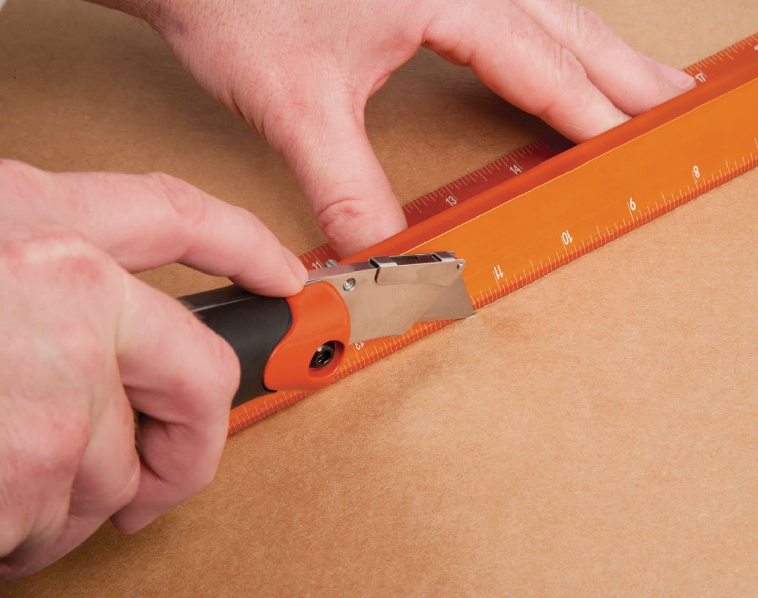 Hands using a utility knife along the SAVAGE No Slip Straight Edge, blade caught by the raised Thumb Saver edge.