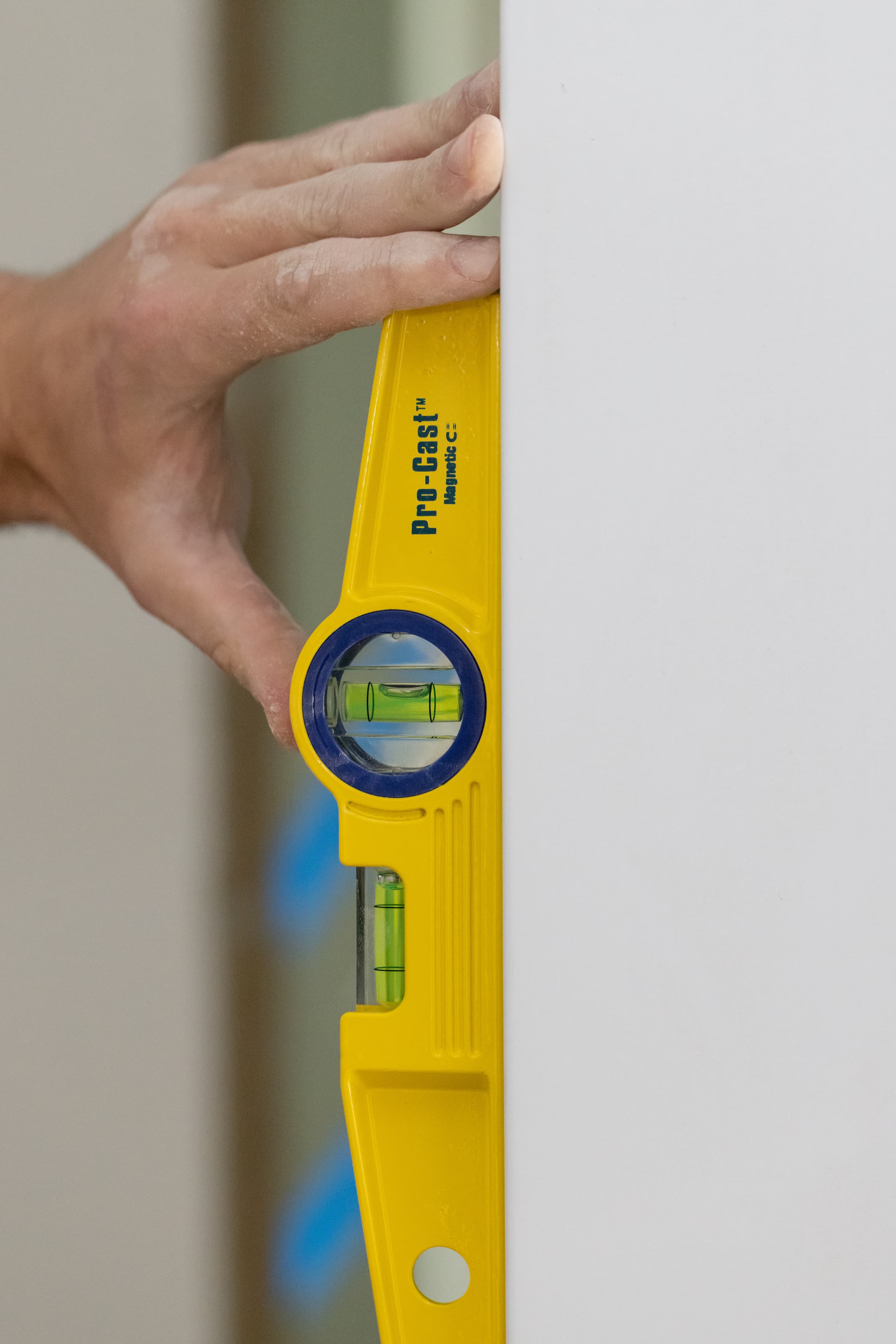 A trades pro setting the Pro-Cast torpedo level against a ferrous surface on a job site.