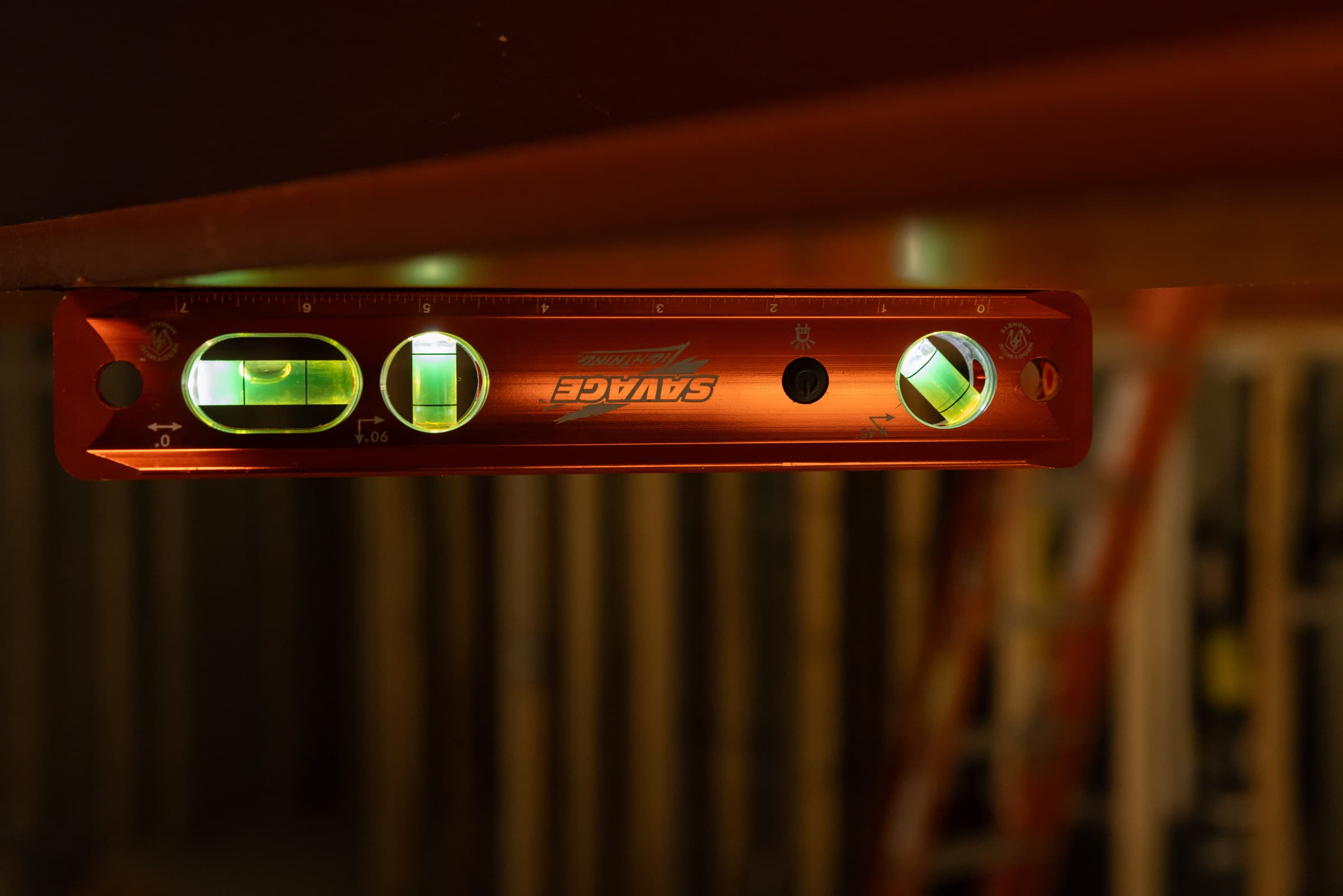 TLL049M Savage® Lighted Torpedo Level glowing in a dark job-site cavity, vials lit by the integrated LED.