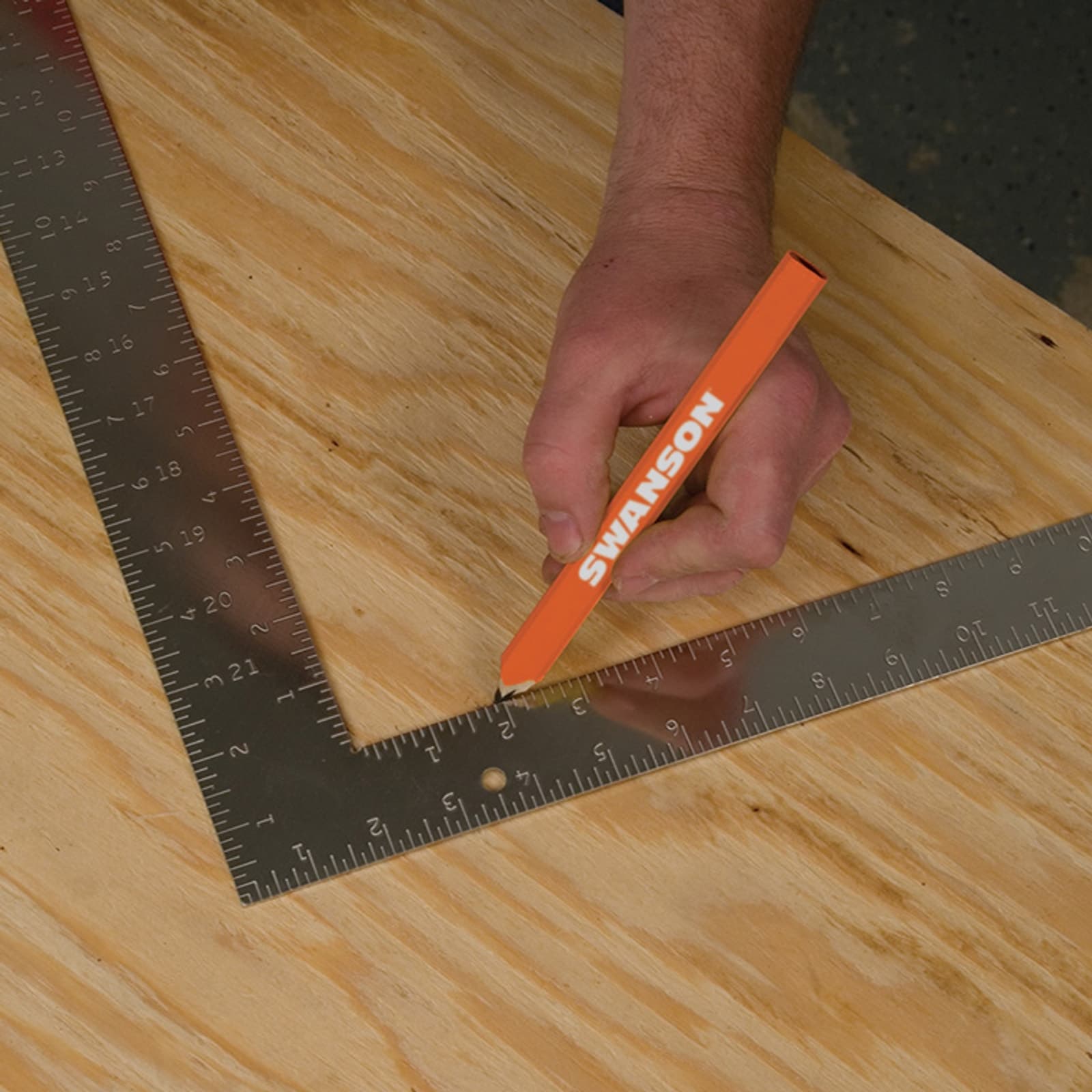 A framer using the Swanson TS157 Steel Carpenter Square on the job site for rafter and stud layout.