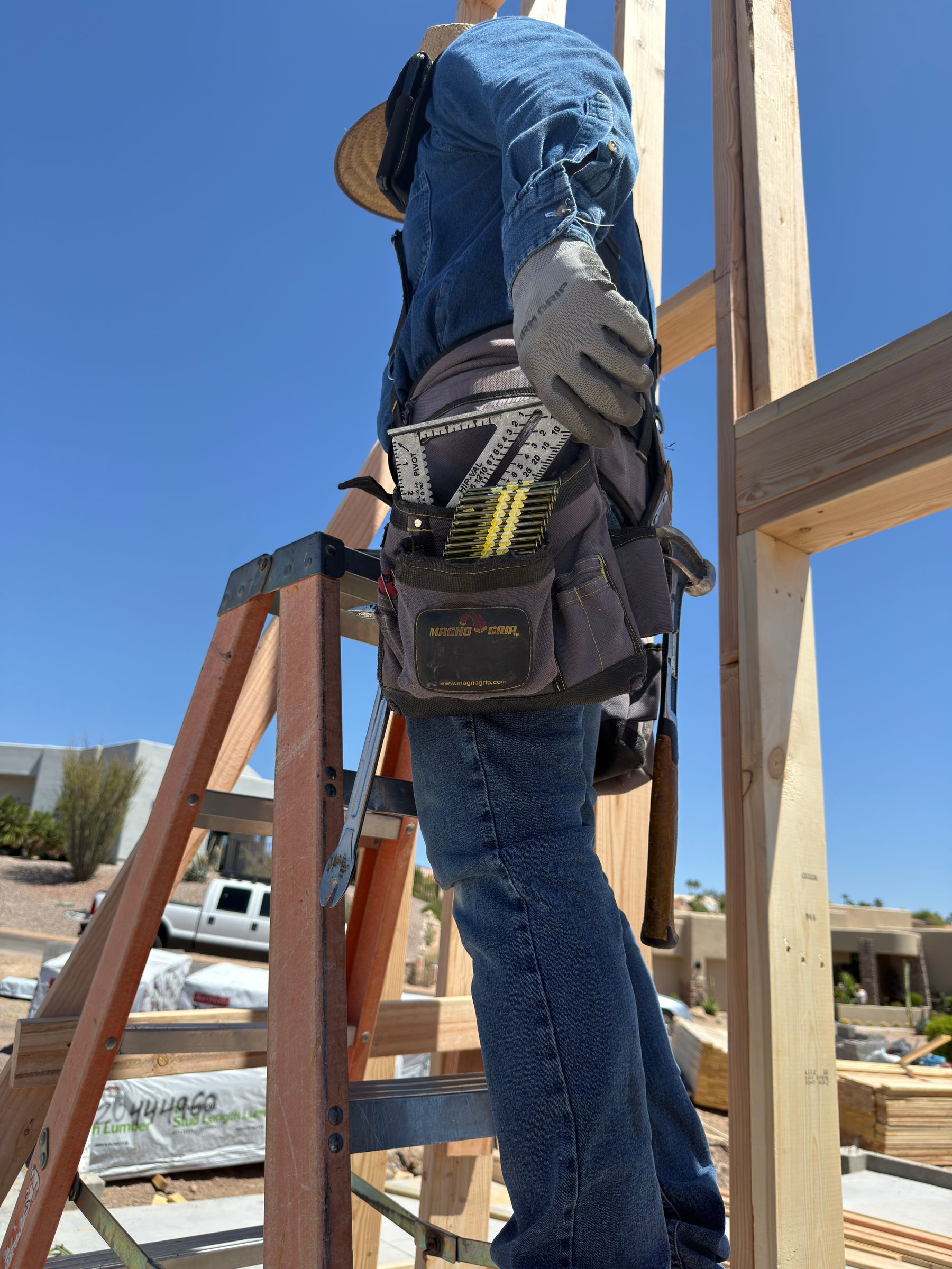 A framer on a ladder reaching into a tool belt for the Swanson Speed® Square